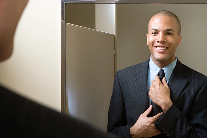 Man looking in mirror reflecting on self awareness